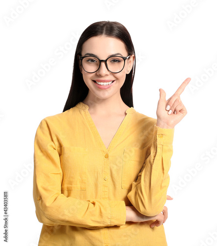 Beautiful young woman wearing stylish sunglasses and pointing at something on white background