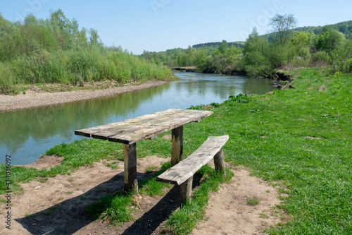 Table and bench made of natural wood for a picnic on the river bank. Summer landscape  nature.