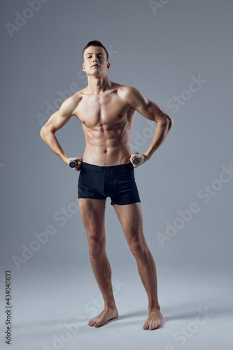 sporty man holding hands on the belt in black shorts inflated body exercise fitness
