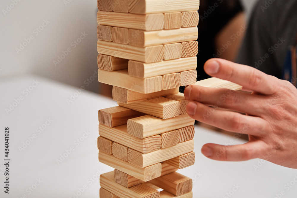Family play board game. Hands take wooden block from tower. Family play board game. Hands take wooden block from tower.
