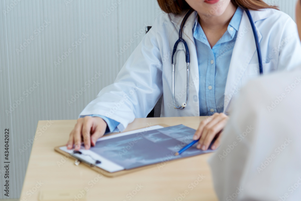 Two asian women doctors discuss meeting doctor's office medical clinic looking x-ray film consulting patient disease. Asian medical lab young women talking together discussing healthcare teamwork Two asian women doctors discuss meeting doctor's office medical clinic looking x-ray film consulting patient disease. Asian medical lab young women talking together discussing healthcare teamwork