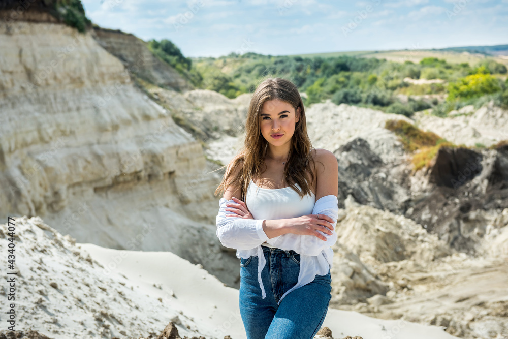 Naklejka premium A young beautiful girl in fashionable casual clothes relax in sand quarry