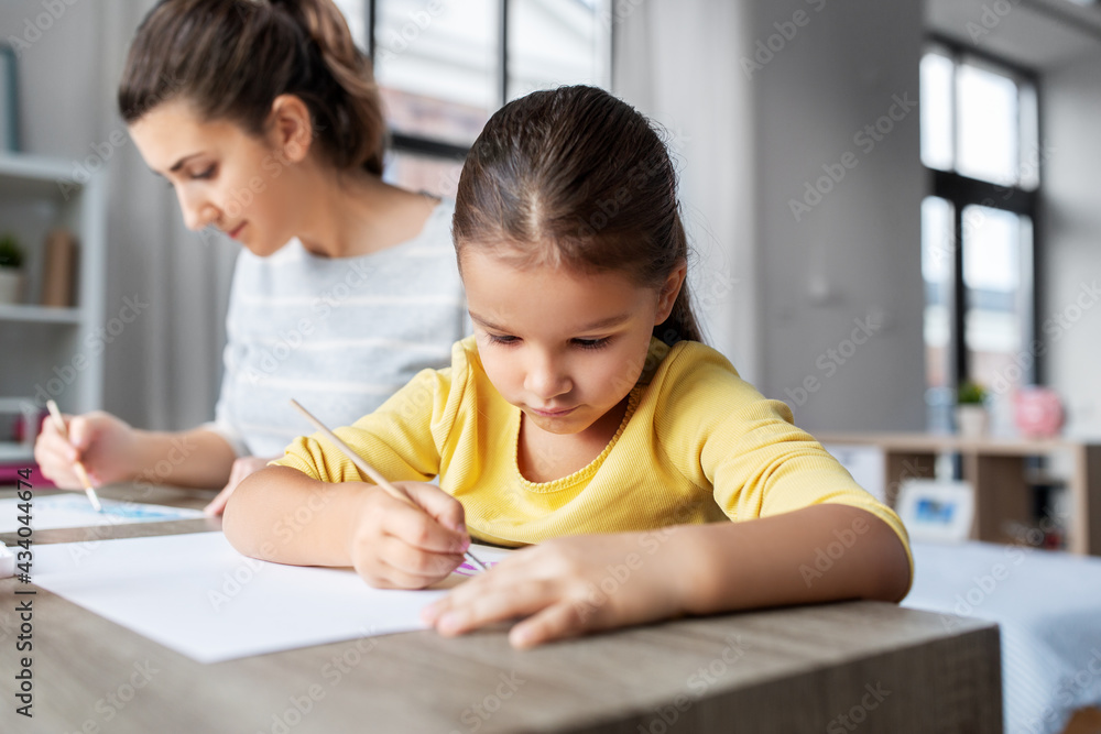 family, motherhood and leisure concept - mother spending time with her little daughter drawing with colors at home family, motherhood and leisure concept - mother spending time with her little daughter drawing with colors at home