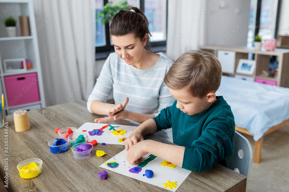 family, creativity and craft concept - mother and little son making picture of modeling clay at home family, creativity and craft concept - mother and little son making picture of modeling clay at home
