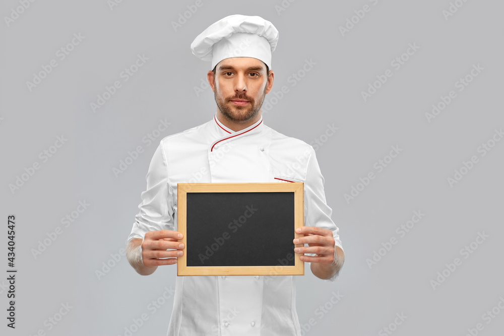 cooking, culinary and people concept - male chef in toque showing chalkboard over grey background cooking, culinary and people concept - male chef in toque showing chalkboard over grey background