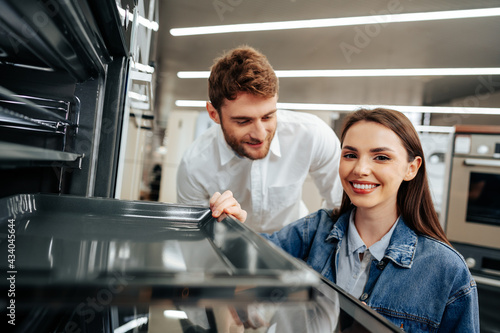 Young couple choosing new electric oven in hypermarket