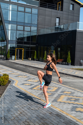 Pretty sports female model doing morning stretching in front of modern glass building © RomanR