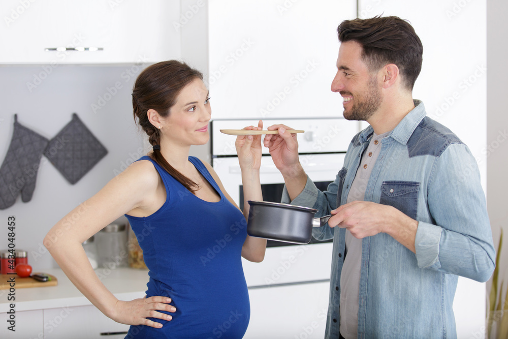 pregnant woman and husband cooking healthy in kitchen pregnant woman and husband cooking healthy in kitchen