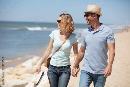 young happy couple walking on beach smiling
