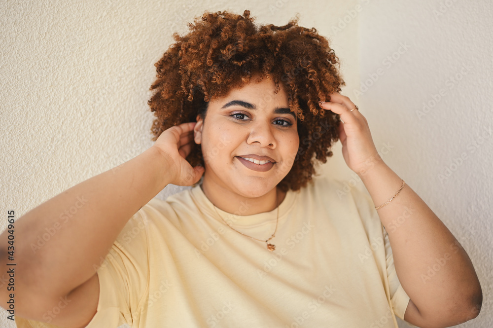 Beautiful happy smiling curvy plus size African black woman afro hair with make up posing in beige t-shirt on white background. Body imperfection, body acceptance, body positive and diversity concept. Beautiful happy smiling curvy plus size African black woman afro hair with make up posing in beige t-shirt on white background. Body imperfection, body acceptance, body positive and diversity concept.