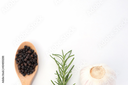 Black pepper grains  fresh rosemary herb and garlic on white background.