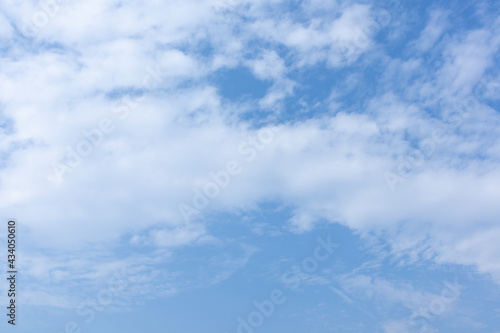 Blue sky with fluffly white scattered clouds day time landscape background.