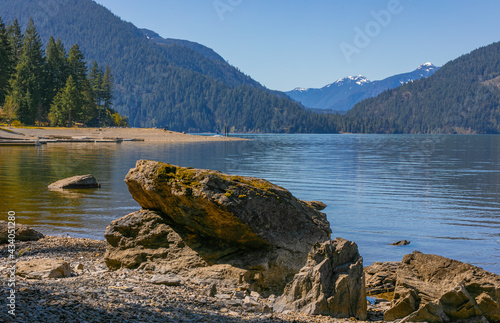 Beautiful landscape of the Harrison lake with large rocks in the foreground and mountains on the background. photo