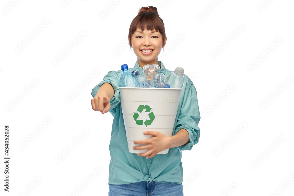 recycling, waste sorting and sustainability concept - smiling young asian woman holding rubbish bin with plastic bottles pointing finger to camera over white background recycling, waste sorting and sustainability concept - smiling young asian woman holding rubbish bin with plastic bottles pointing finger to camera over white background