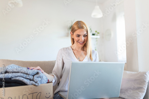 Donation Concept. Woman holding a Donate Box with full of Clothes. Woman holding a book and clothes donate box. Clothes in box for concept donation and reuse recycle