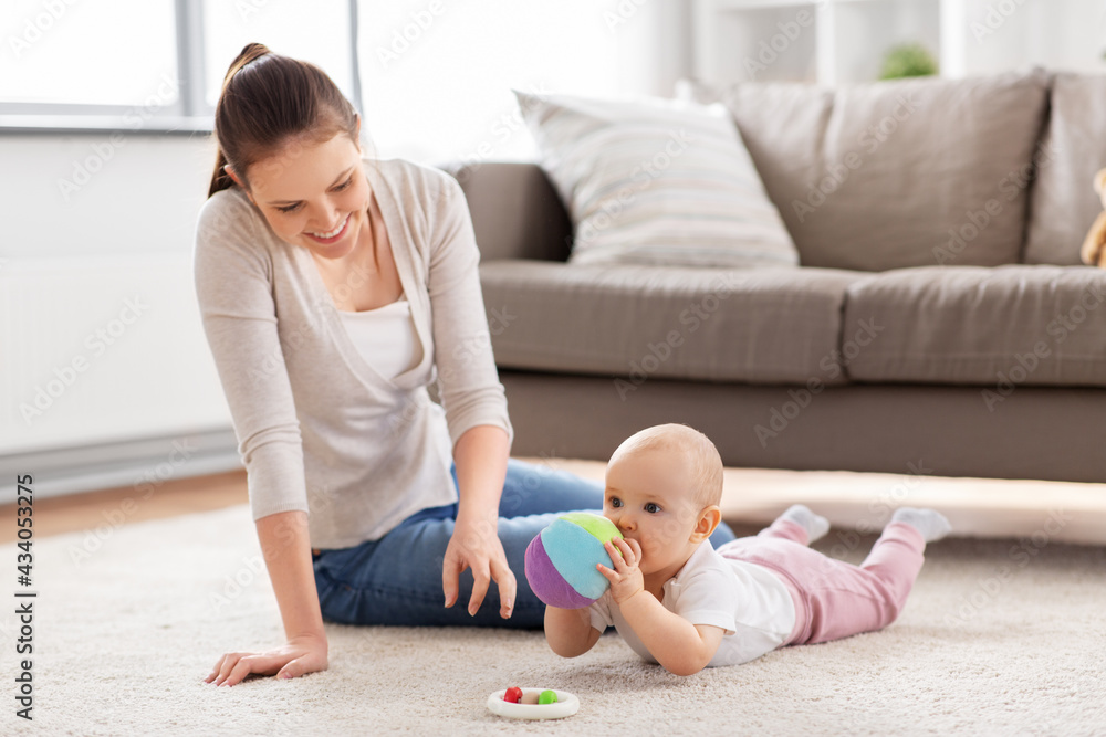 family, motherhood and people concept - happy smiling mother and little baby daughter playing with soft ball toy on floor at home family, motherhood and people concept - happy smiling mother and little baby daughter playing with soft ball toy on floor at home