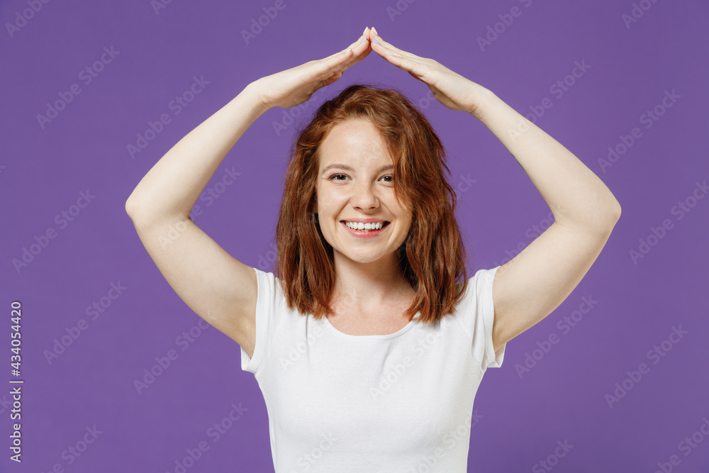 Young fun smiling happy woman wearing white basic t-shirt hold folded hands above head like house roof, stay home isolated on dark violet color background studio portrait. People lifestyle concept Young fun smiling happy woman wearing white basic t-shirt hold folded hands above head like house roof, stay home isolated on dark violet color background studio portrait. People lifestyle concept