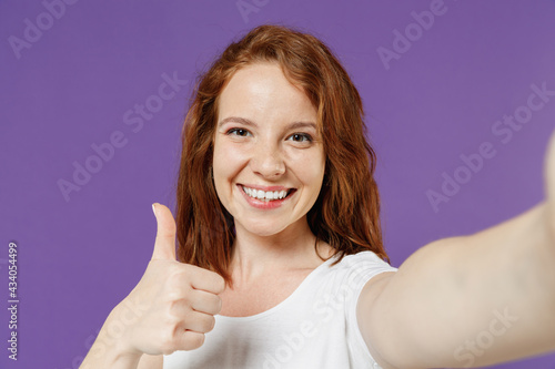 Wallpaper Mural Close up young smiling happy friendly redhead woman 20s wear white basic casual t-shirt doing selfie shot on mobile phone show thumb up like gesture isolated on dark violet color background studio Torontodigital.ca
