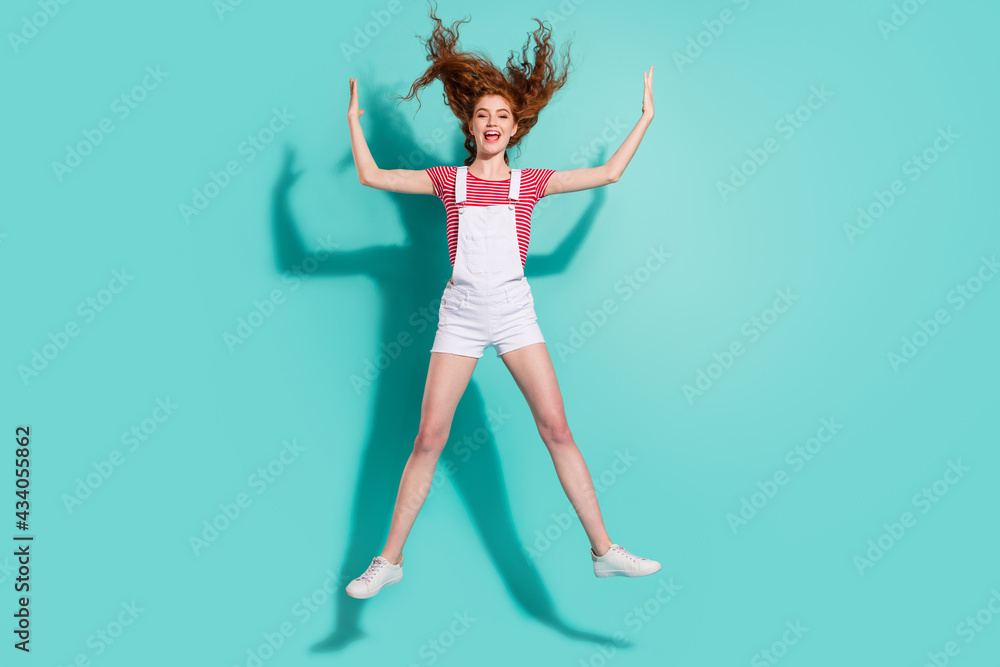 Obraz premium Full length body size view of attractive cheerful girl jumping having fun throwing hair isolated bright blue color background