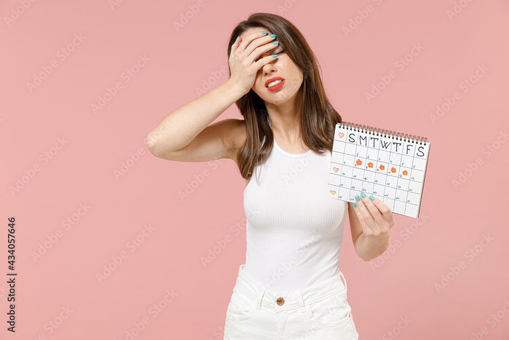Young woman in white clothes hold female periods calendar for checking menstruation days put hand face facepalm epic fail gesture isolated on pink background Medical healthcare gynecological concept Young woman in white clothes hold female periods calendar for checking menstruation days put hand face facepalm epic fail gesture isolated on pink background Medical healthcare gynecological concept