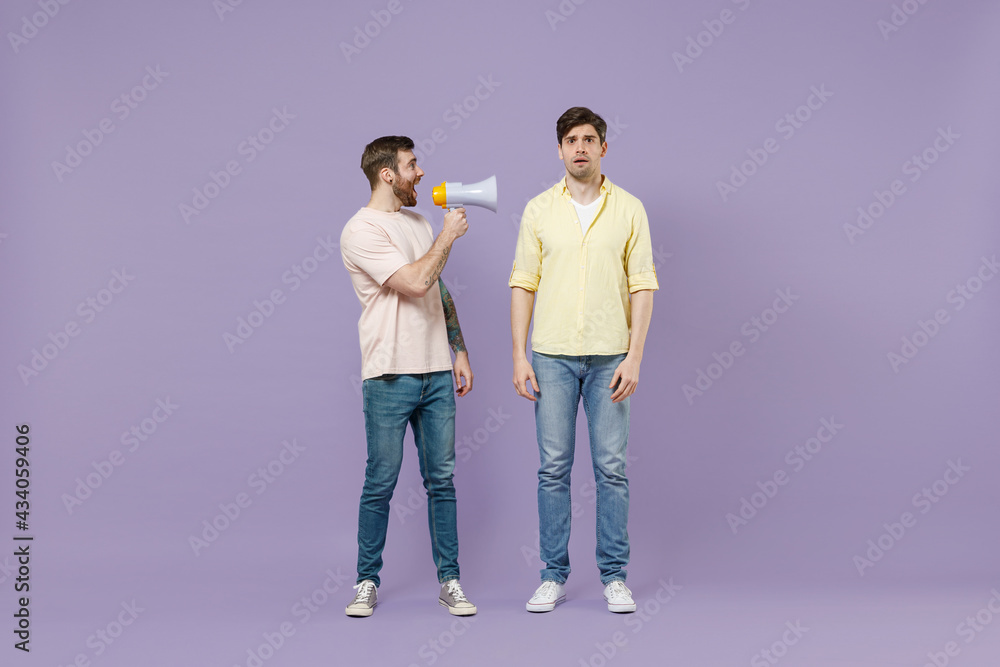 Fototapeta premium Full length shocked confused disappointed young men friends together in t-shirt scream hot news in megaphone fooling around isolated on purple background studio. People lifestyle friendship concept