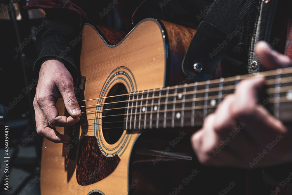Fototapeta premium Guitarist playing acoustic guitar in the dark close up.