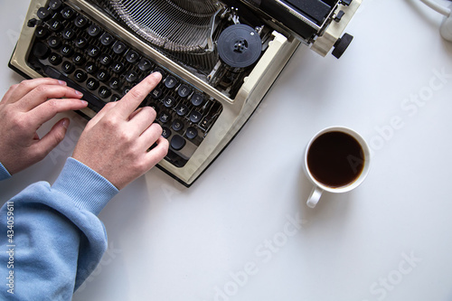 Woman's hand typing on a vintage typewriter top view.