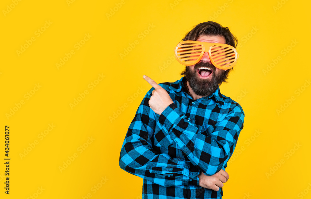 happy bearded man wearing funny party glasses and pointing finger on yellow background, copy space, best offer happy bearded man wearing funny party glasses and pointing finger on yellow background, copy space, best offer