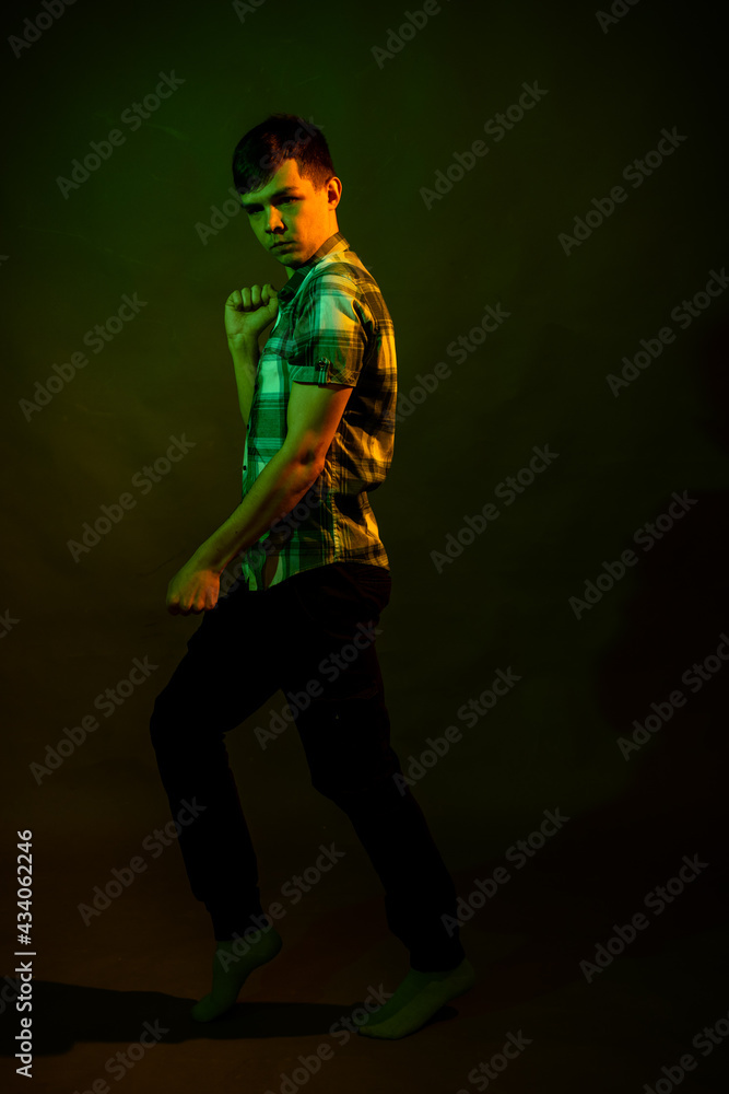 The guy in the checkered shirt dances, illuminated by orange and green light The guy in the checkered shirt dances, illuminated by orange and green light