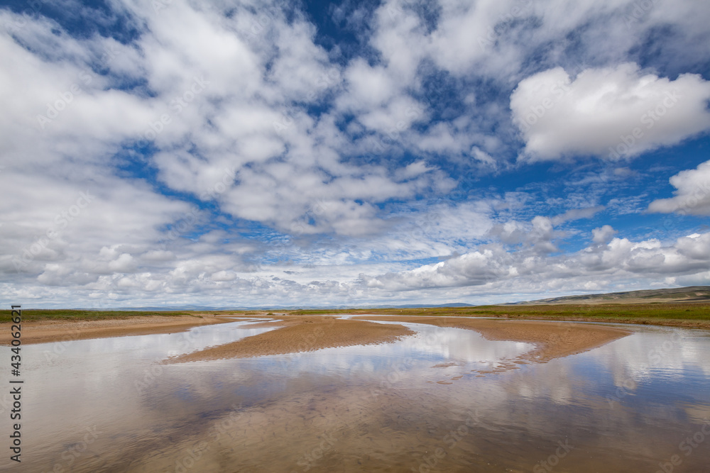 Landscape with river and sky with white clouds reflecting in the water on the Tibetan plateau, Qinghai province, China