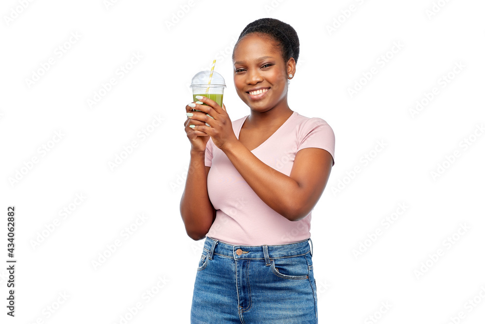 diet, healthy eating and detox concept - happy smiling young african american woman drinking green vegetable juice or smoothie from plastic cup with paper straw over white background diet, healthy eating and detox concept - happy smiling young african american woman drinking green vegetable juice or smoothie from plastic cup with paper straw over white background