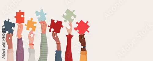 Group of multi-ethnic business people with raised arms holding a piece of jigsaw. Colleagues of diverse races and culture. Cooperate and collaborate. Concept of teamwork and success photo