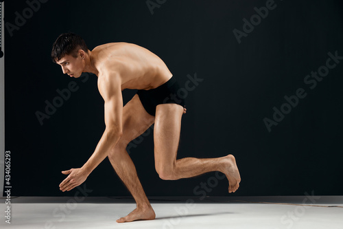 sporty man in black shorts with a muscular body on a dark background