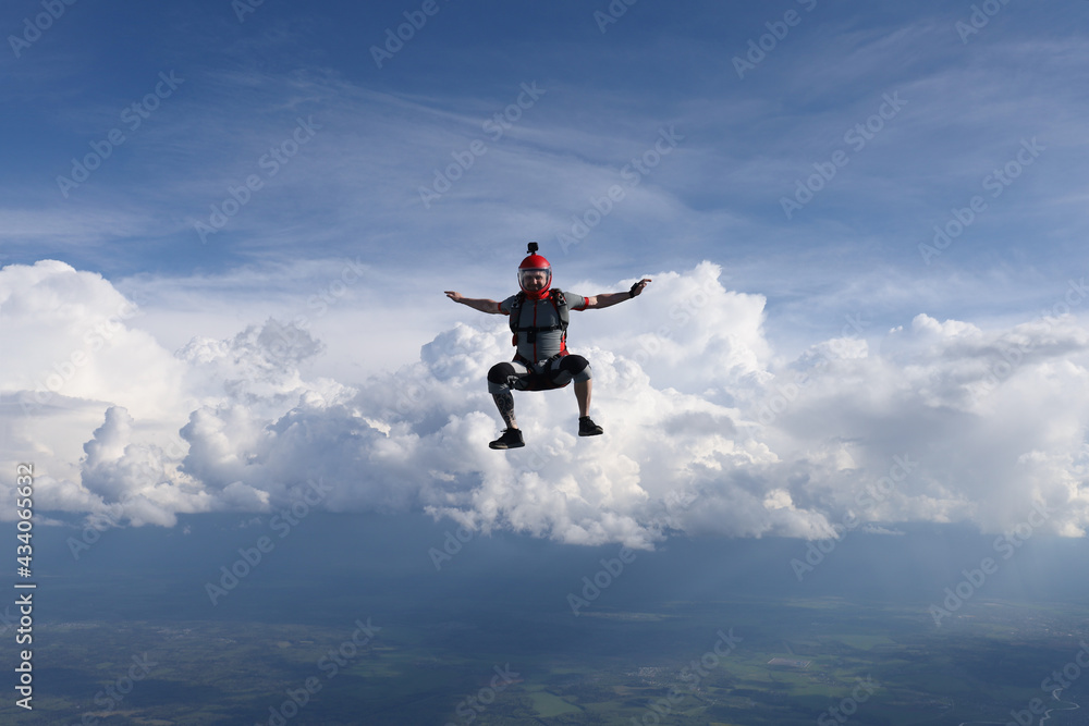 Skydiving. A guy is falling in sit position. Amazing clouds are in the background.