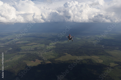 A guy is falling in the sky, in the background beautiful clouds.