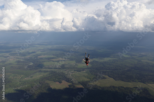 A guy is falling in the sky, in the background beautiful clouds.