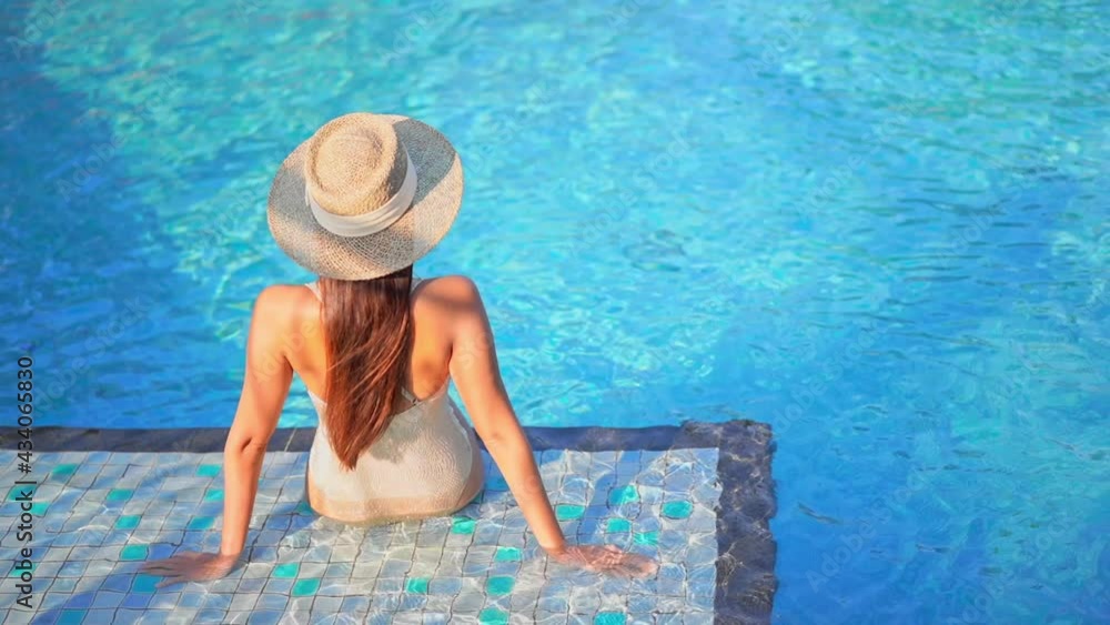 Back view of the fit woman sitting in shallow water on the edge of a ...