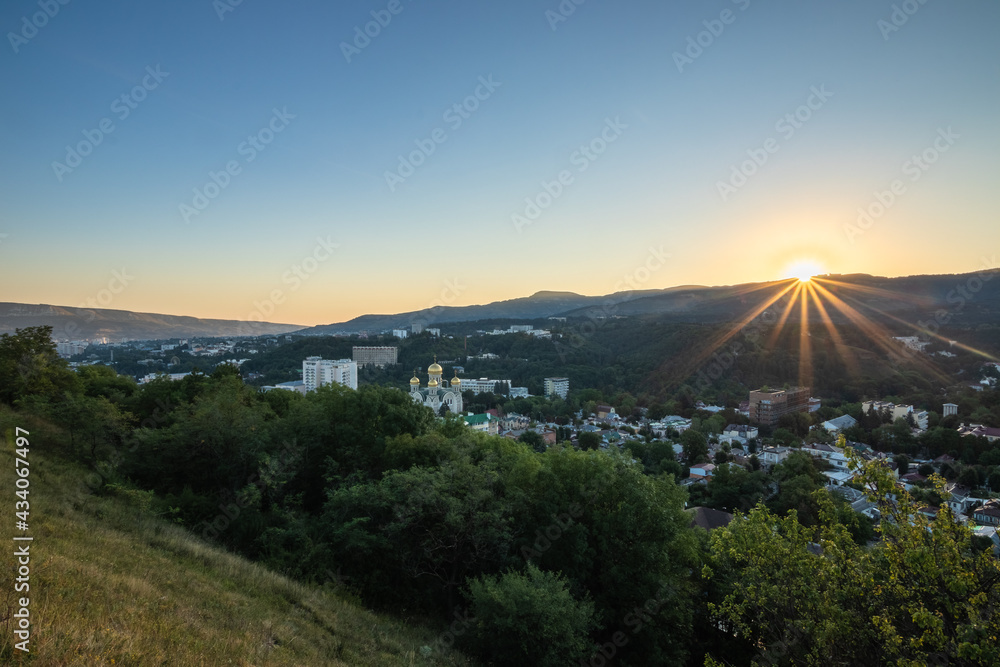 Fototapeta premium Sunrise over mountains and town Kislovodsk at morning.