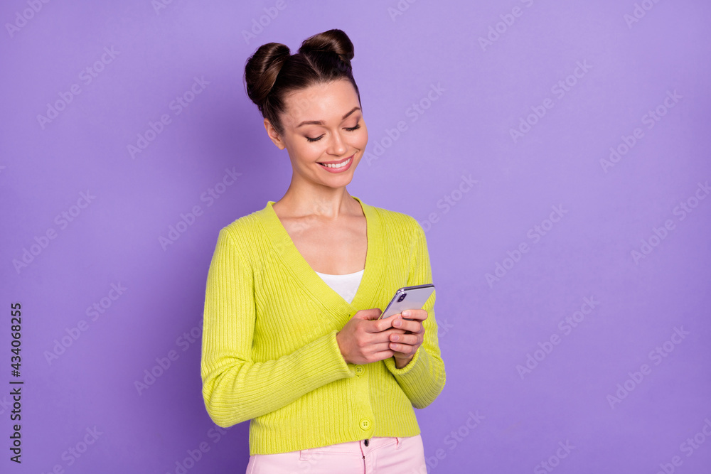 Photo of young pretty happy cheerful smiling girl hold smartphones browsing in internet isolated on purple color background Photo of young pretty happy cheerful smiling girl hold smartphones browsing in internet isolated on purple color background