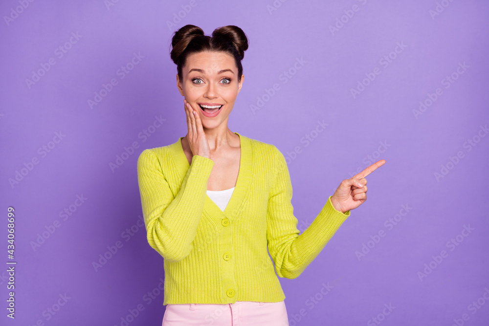 Photo portrait of young girl in green cardigan showing finger blank space touching cheek isolated on pastel purple color background Photo portrait of young girl in green cardigan showing finger blank space touching cheek isolated on pastel purple color background