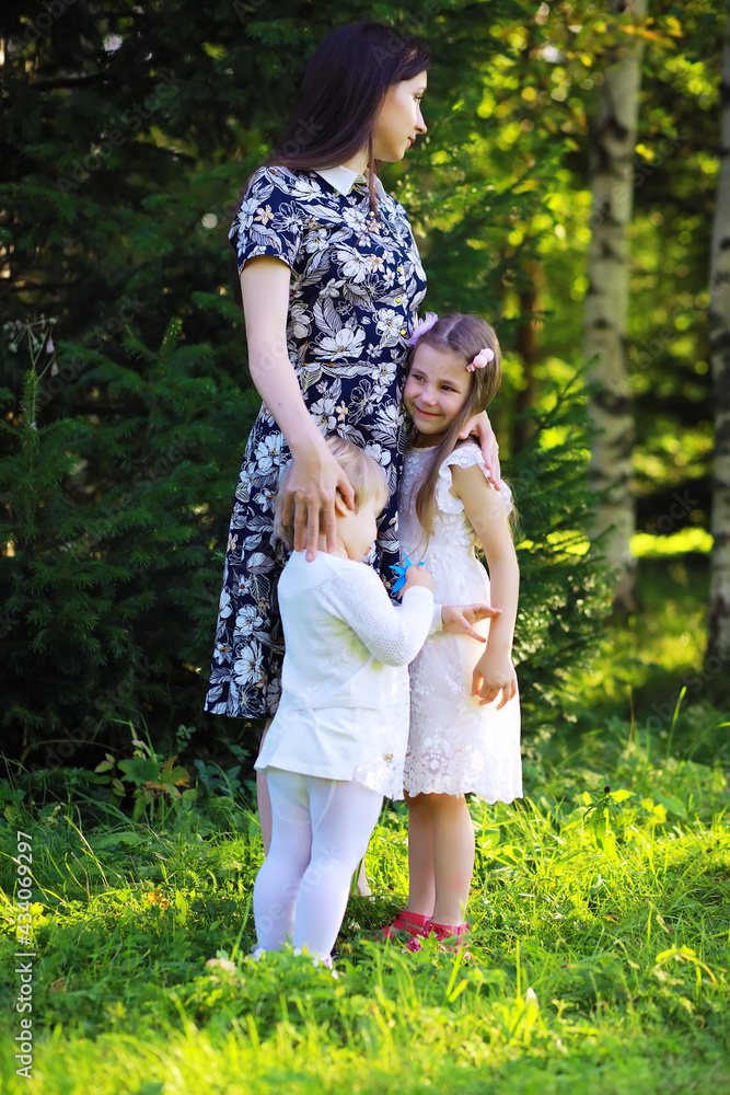 Fototapeta premium Young large family on a summer morning walk. Beautiful mother with children is playing in the park.
