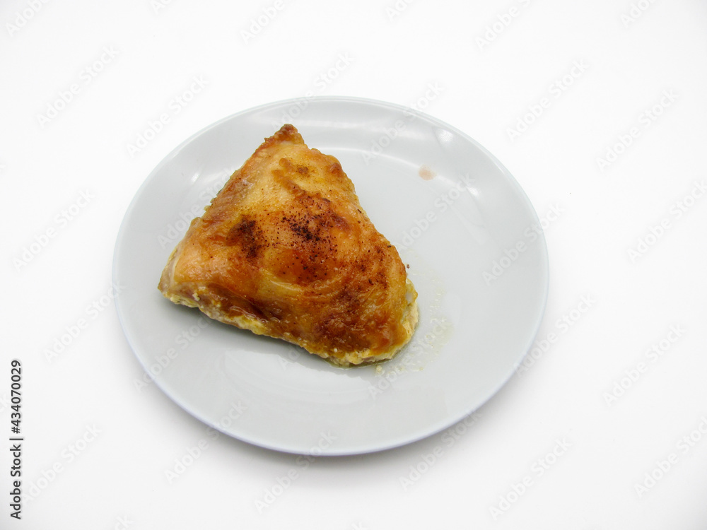 baked chicken thigh on a gray plate on a white background baked chicken thigh on a gray plate on a white background