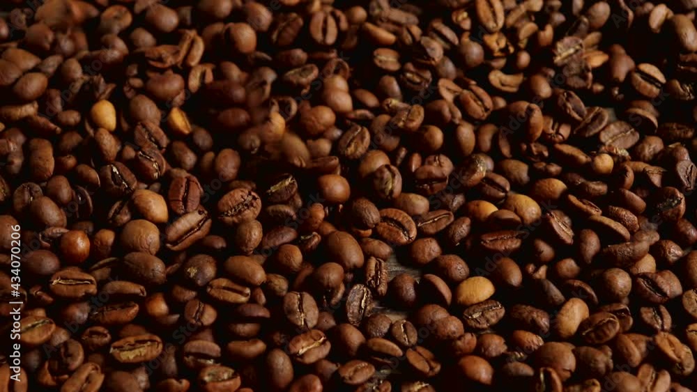 Roasted coffee beans fall on a wooden surface. Slow motion. Roasted coffee beans fall on a wooden surface. Slow motion.