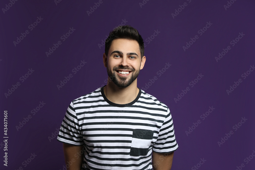 Fototapeta premium Young man laughing on purple background. Funny joke