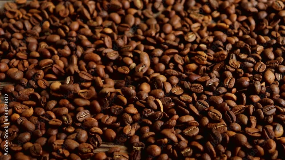 Roasted coffee beans fall on a wooden surface. Slow motion. Roasted coffee beans fall on a wooden surface. Slow motion.