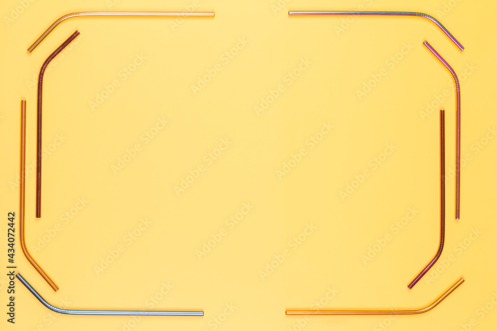 Multicolored reusable stainless steel straws on pastel yellow background. Top view, copy space