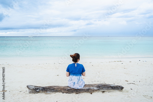 one lady sitting on log and looking away to the beach