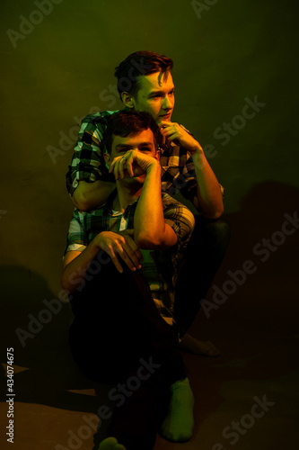 Two guys sitting on the floor in the studio. illuminated by yellow and green light