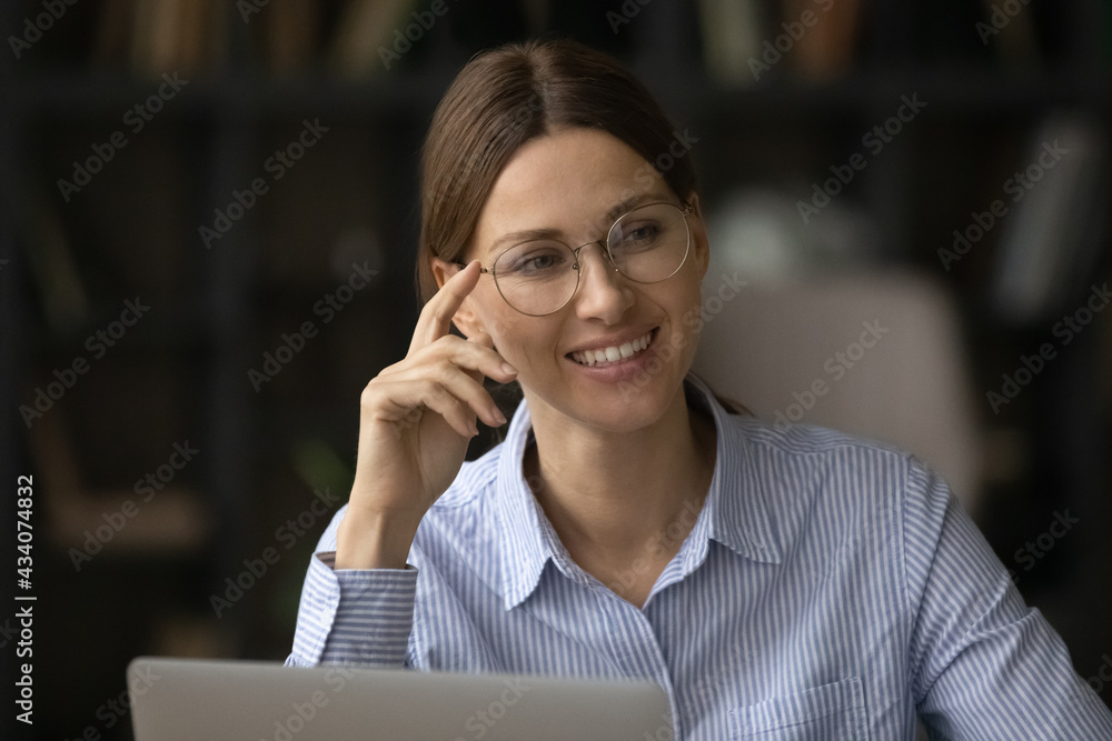 Business lady. Happy businesswoman in stylish glasses look above pc screen show strong white teeth in healthy beautiful smile. Optimistic young female office worker smiling distracted from online job Business lady. Happy businesswoman in stylish glasses look above pc screen show strong white teeth in healthy beautiful smile. Optimistic young female office worker smiling distracted from online job