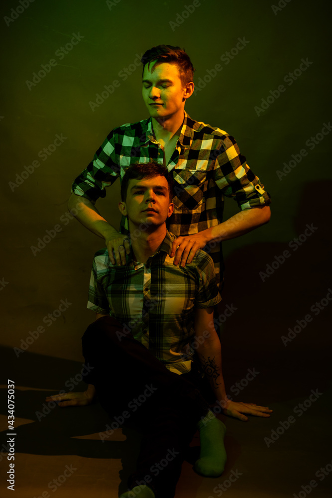 Fototapeta premium Two guys sitting on the floor in the studio. illuminated by yellow and green light